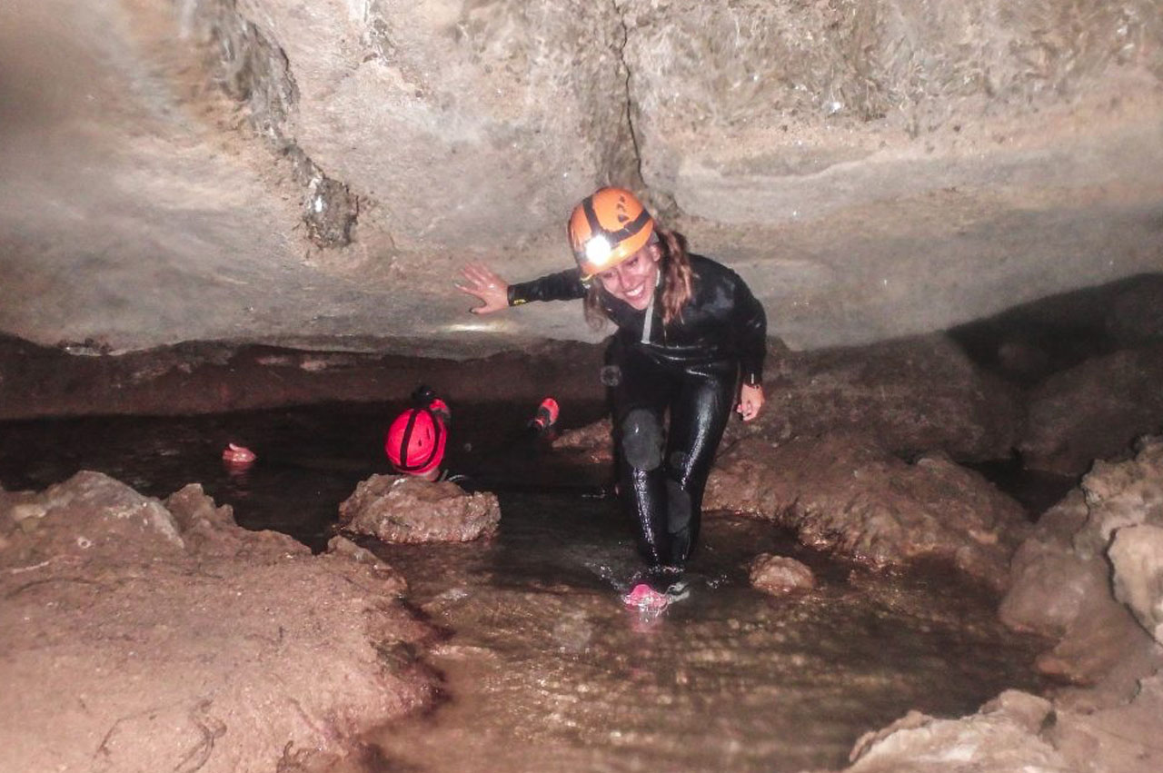 chica agachada caminando por la cueva del agua